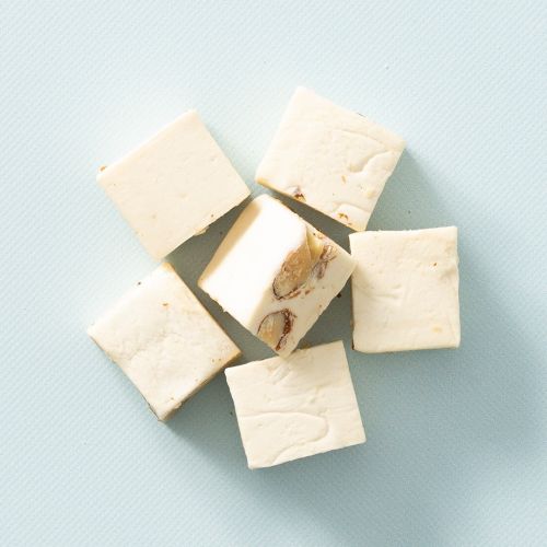 Roomnougat met amandelen op een lichtblauwe achtergrond Roomnougat met amandelen op een lichtblauwe achtergrond