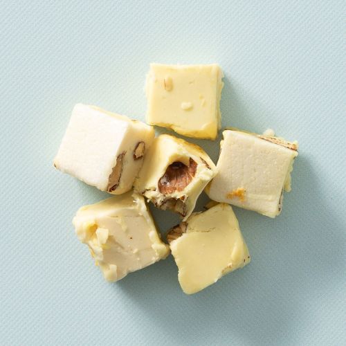 Blokjes soft nougat limoncello met noten op een lichtblauwe achtergrond Blokjes soft nougat limoncello met noten op een lichtblauwe achtergrond
