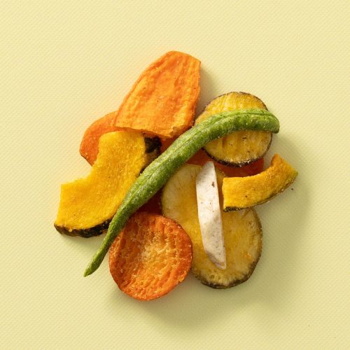 Groentechips van verschillende groenten op een lichtgele achtergrond Groentechips van verschillende groenten op een lichtgele achtergrond