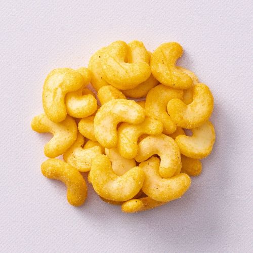 Spicy cashew bites op lichtpaarse achtergrond Spicy cashew bites op lichtpaarse achtergrond