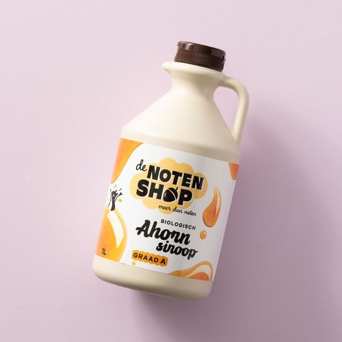 Fles biologische ahornsiroop graad A op een lichtroze achtergrond Fles biologische ahornsiroop graad A op een lichtroze achtergrond
