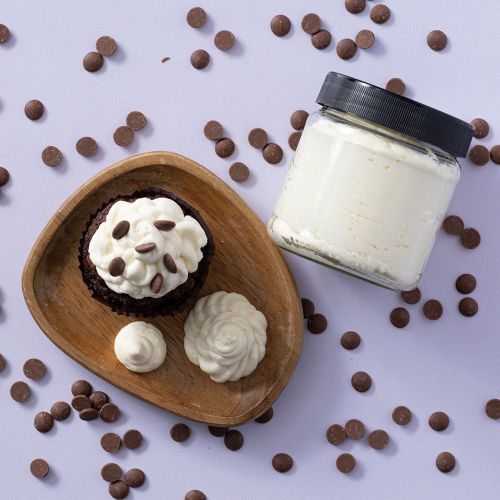 Cream cheese frosting op een houten plankje met cupcakes en potje cream cheese