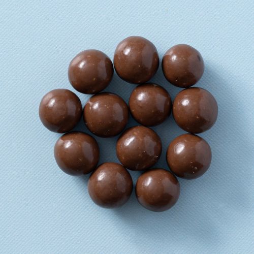 Chocolade macadamia noten op een lichtblauwe achtergrond Chocolade macadamia noten op een lichtblauwe achtergrond