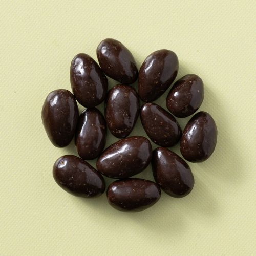 Pure chocolade amandelen in een rondje op een gele achtergrond Pure chocolade amandelen in een rondje op een gele achtergrond