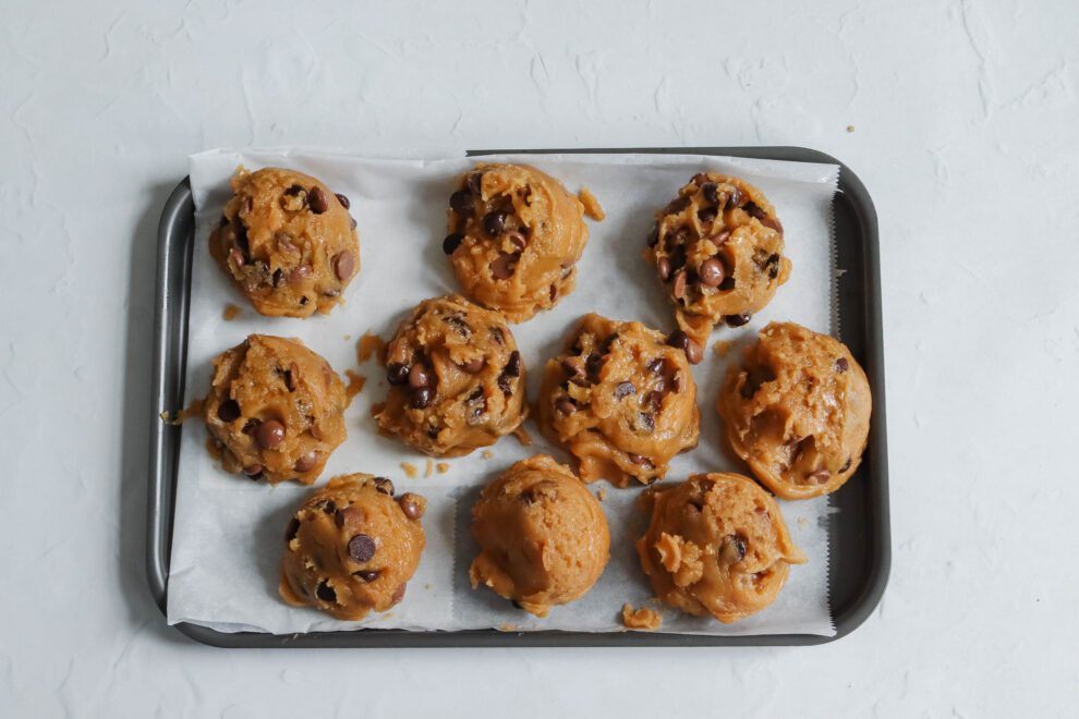 Bolletjes deeg voor chocolate chip cookies op de bakplaat.