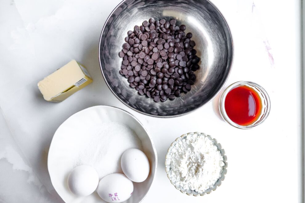 Alle ingredienten in schalen voor een Tiramisu brownie met boter, chocoladedruppels, eieren, bloem, suiker, vanille extract en meer