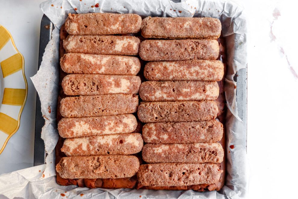 Vierkante bakvorm met lange vingers bovenop het browniebeslag