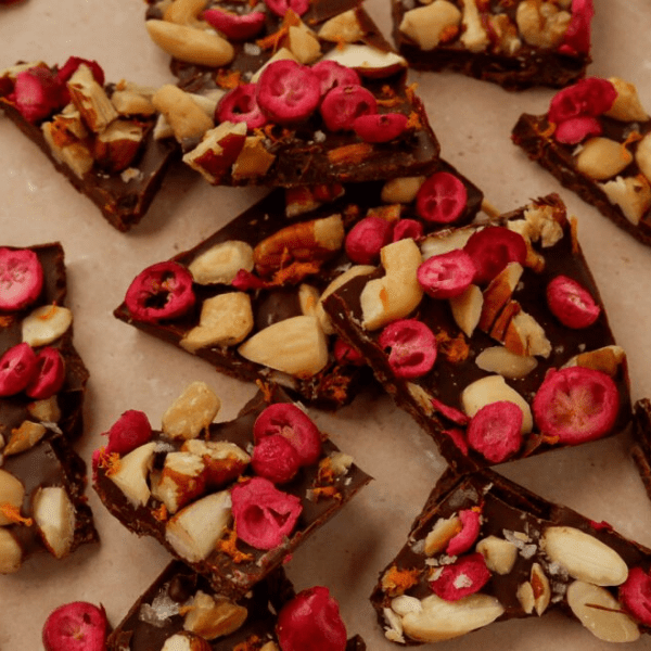Chocoladebark met cranberry, noten en sinaasappel op een schaal.