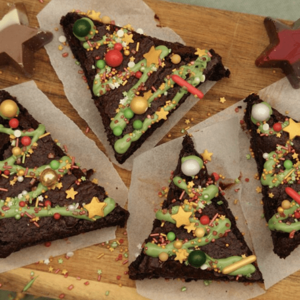 Fudgy kerst brownies met kerstdecoratie op een houten plank.